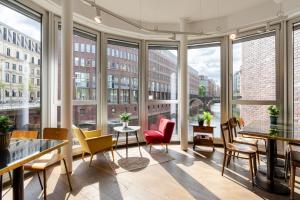 ein großer Raum mit Stühlen und Tischen und großen Fenstern in der Unterkunft Ruby Lotti Hotel Hamburg by IHG in Hamburg