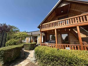 a large wooden house with a porch and some bushes at Paradise Villa in Gracanica