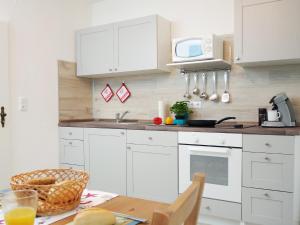 a kitchen with white cabinets and a table and a microwave at Fischerhaus Bremerhaven in Bremerhaven