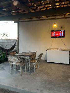 a table and chairs and a television on a wall at Suíte Adam 1 em Caraíva com piscina 900m da Vila in Caraíva