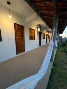 a porch with a hammock on the side of a house at Suíte Adam 1 em Caraíva com piscina 900m da Vila in Caraíva