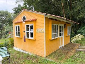 a small yellow house with a bench in a yard at Cabañas Creation Garden - Espacio de Vida Saludable in San Francisco +2 photos