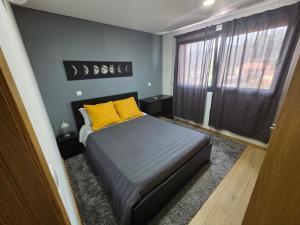 a bedroom with a bed with yellow pillows and a window at Paisagem&Charme in Celorico de Basto