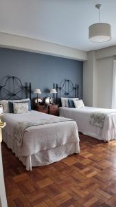 two beds in a room with blue walls and wooden floors at Solar De La Plaza in Salta