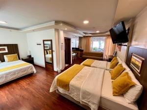 a hotel room with two beds and a flat screen tv at Casa Hidalgo Ecuador in Cumbayá +39 photos