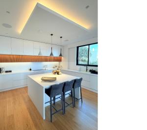 a kitchen with white cabinets and a white island with stools at Wiile State in Athánatoi