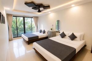 a bedroom with two beds and a large window at SAVRAJ Stay Beach Goa in Candolim