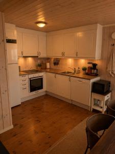 a kitchen with white cabinets and a wooden floor at Håvi Solsiden 11C in Trysil