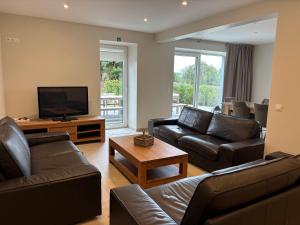a living room with leather furniture and a flat screen tv at La Petite Reine in Bertrix