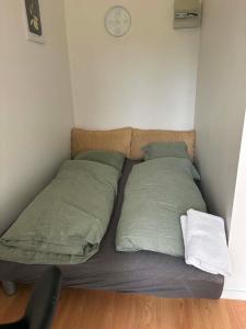 a bed with two pillows and a clock on the wall at Mølhøjvej lejlighed in Andrup