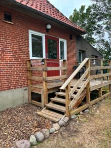 a wooden ramp leading to a house with a red door at Mølhøjvej lejlighed in Andrup