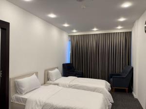 a hotel room with two beds and two chairs at Hotel Mihad sulaymaniyah in As Sulaymānīyah