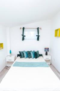 a white bedroom with a large bed with blue pillows at Déjá-Vu Apartmanház in Szigetvár +34 photos