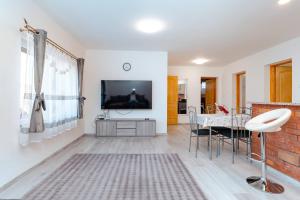 a living room with a television and a table with chairs at Déjá-Vu Apartmanház in Szigetvár