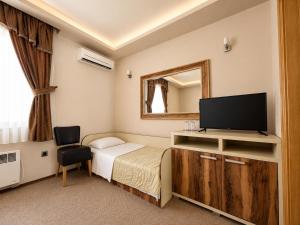 a bedroom with a bed and a tv and a mirror at Semberski Salaš Intergaj Hotel in Bijeljina