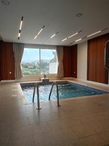 a large swimming pool in a building with a large window at استراحات وفلل رفايا in Abha