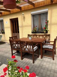 a wooden table and chairs on a patio with flowers at Handó Porta in Szenna