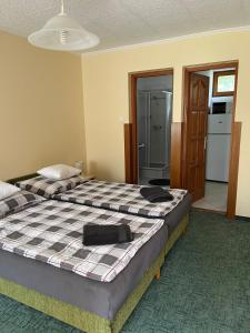 a bedroom with two beds and a kitchen with a refrigerator at Handó Porta in Szenna