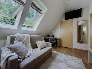 a living room with a couch and two windows at Zacisze pod Tatrami in Suche