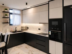 a kitchen with white cabinets and a black appliance at IDeal Sea View Apartment in Vlorë