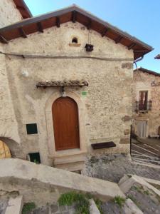 a stone building with a wooden door on it at Casa vacanza da GIGI in Calascio