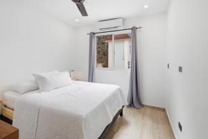 a white bedroom with a bed and a window at Casa Docia Hotel in Santa Bárbara de Samaná +33 photos