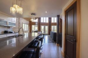 a kitchen with a long counter with a sink and chairs at Chinook 172 in Sainte-Marguerite