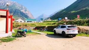 a car parked next to a motorcycle on a dirt road at Eden Garden Resort Batakundi in Naran