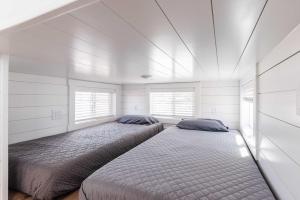 two beds in a bedroom with white walls and windows at Zion Basecamp Private Hot Tub Near Trails in Apple Valley