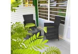 zwei Stühle auf einer Veranda mit Pflanzen in der Unterkunft Hotel Le Rotabas in Sainte-Anne