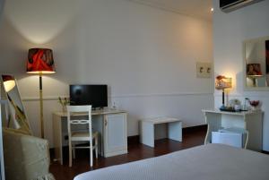 a bedroom with a bed and a desk with a television at B&B Palazzo Sant'Alfano in Catania