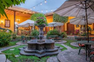 a fountain in a courtyard with tables and umbrellas at Hotel Casa Antigua by AHS in Antigua Guatemala