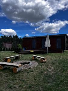 a cabin with benches and an umbrella in the yard at Osada Rolbik in Leśno +19 photos
