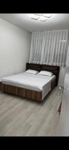 a bedroom with a bed with white sheets and a wooden floor at Nart Apartament in Prizren