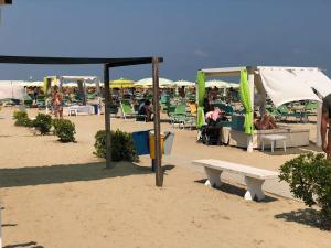 eine Gruppe von Sonnenschirmen und eine Bank an einem Strand in der Unterkunft Hotel Jasmine Beach in Rimini