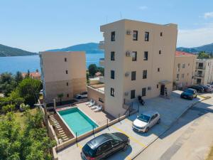 a building with a pool and two cars parked in a parking lot at Iva Apartment in Kumbor