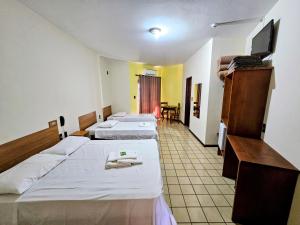 a hotel room with three beds and a tv at Hotel Vivenda das Cachoeiras in Brotas