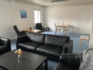 a living room with a black leather couch and a table at Hotel Arctic Circle in Kangerlussuaq