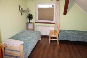 a bedroom with two beds and a window and a chair at Bocianówka 5 in Wężówka