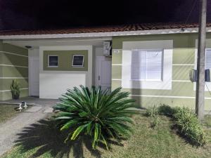 a green and white house with a plant in front of it at Cantinho das Orquídeas! in Pelotas