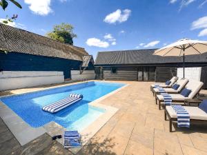 a swimming pool with lounge chairs and an umbrella at 6 Bed in Ardleigh oc-b35089 in Ardleigh