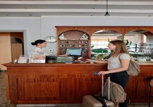 Eine Frau steht mit einem Koffer an einer Kasse. in der Unterkunft Hotel Jasmine Beach in Rimini