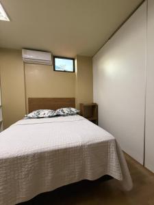 a bedroom with a white bed and a window at LOFT Centrico in Ciudad del Este