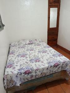 a bed with a floral comforter in a room at Hostal Expansion in San Juan del Sur