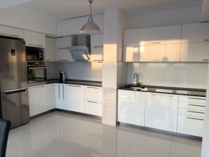 a kitchen with white cabinets and stainless steel appliances at Matey Luxury Sky Apartment in Bitola