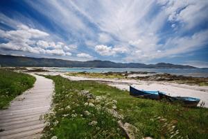 two boats sitting on a sandy beach next to a beach at Apartamento Mar de Carnota in San Mamede de Carnota