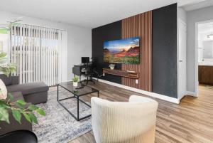 a living room with a couch and a tv on a wall at Tempe Hideaway Luxe Amenities Parking in Tempe