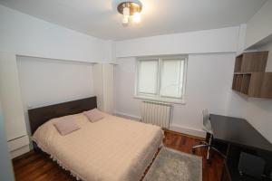 a bedroom with a bed and a desk and a window at M-Buf Center Apartament in Gura Humorului