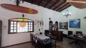 a dining room with a table and a surfboard on the wall at Pousada Pontal de Santa Marina - Caraguatatuba in Caraguatatuba