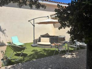 a patio with chairs and a table and an umbrella at Au Petit Bueix in Sillans-la Cascade